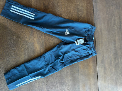 Blue Adidas pants with white stripes on a wooden surface