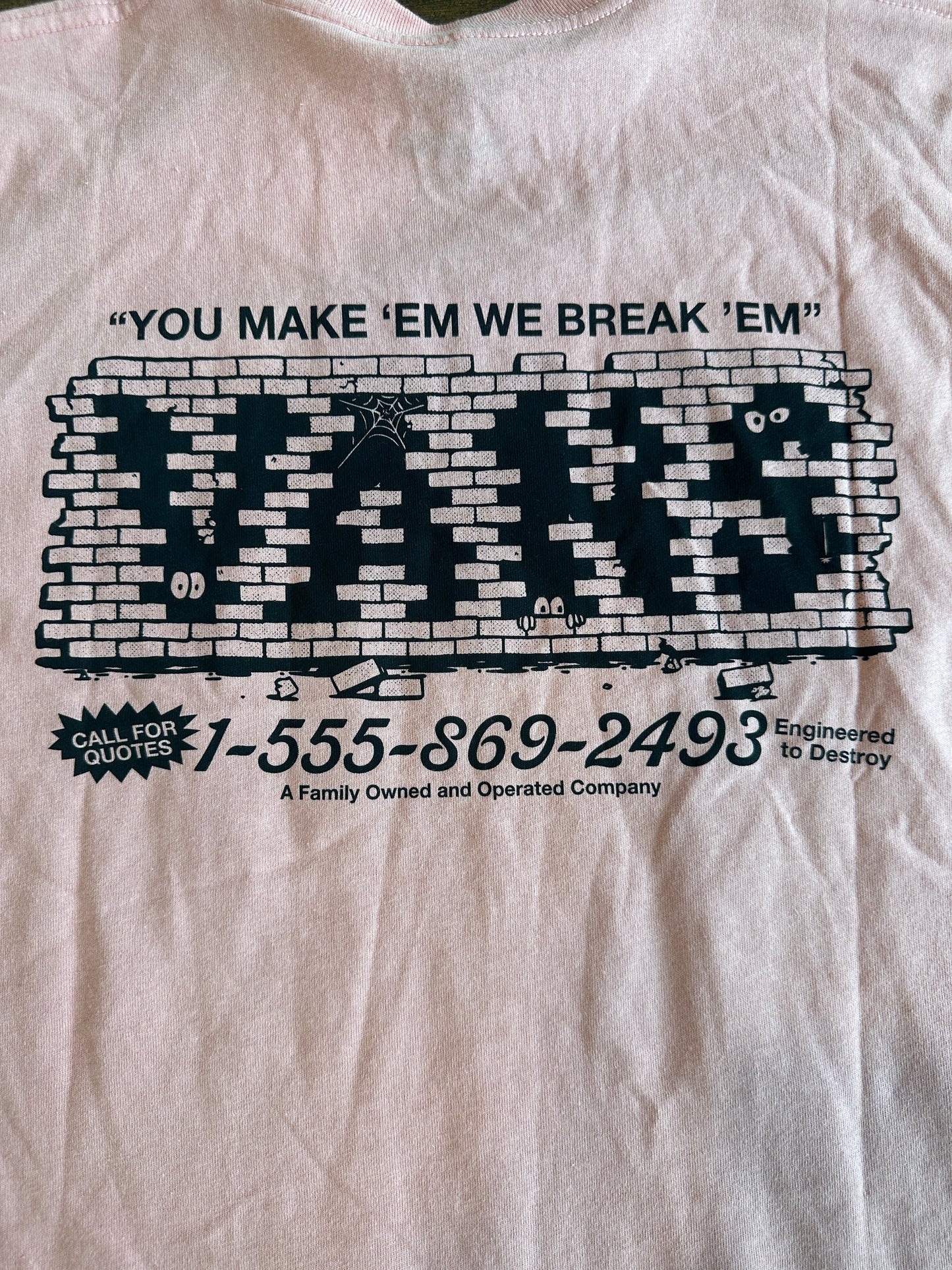 Pink t-shirt with black graphic design and text on a white background