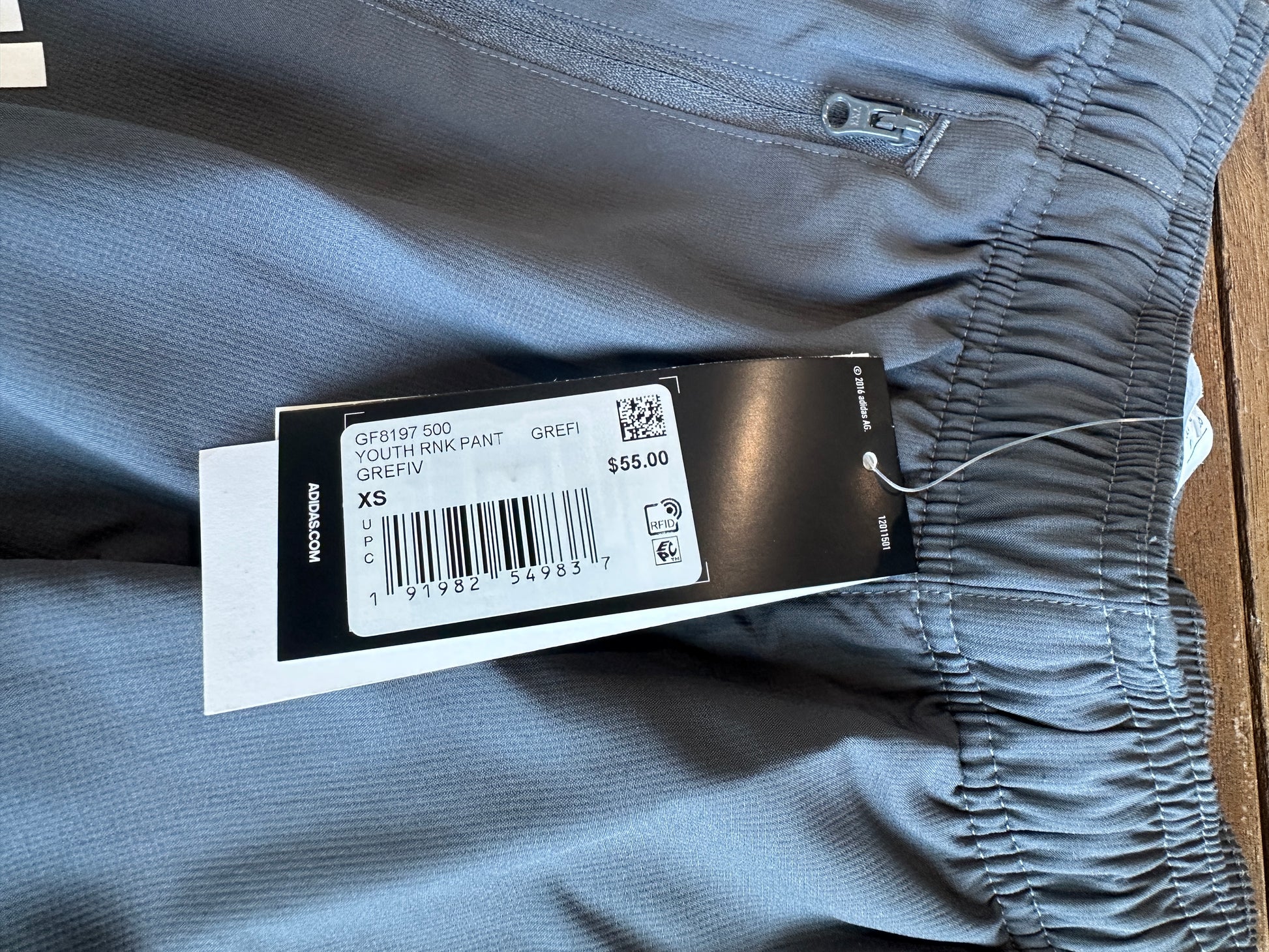 Gray pants with a brand tag on a wooden surface